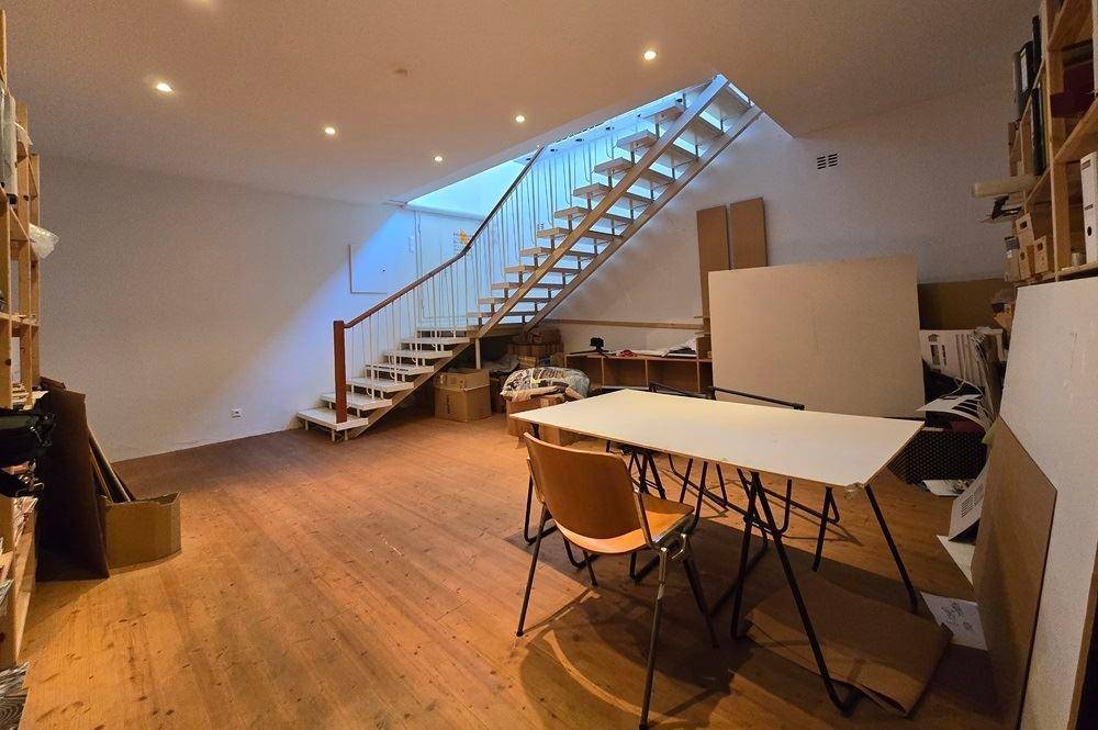 Offener Arbeitsbereich mit einer modernen Holztreppe, einem Arbeitstisch und Regalen.
