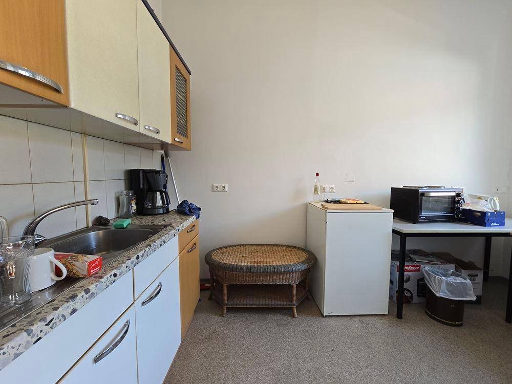 Kleine Küchenzeile mit Spüle, Kühlschrank und Mikrowelle, ideal für Pausen.