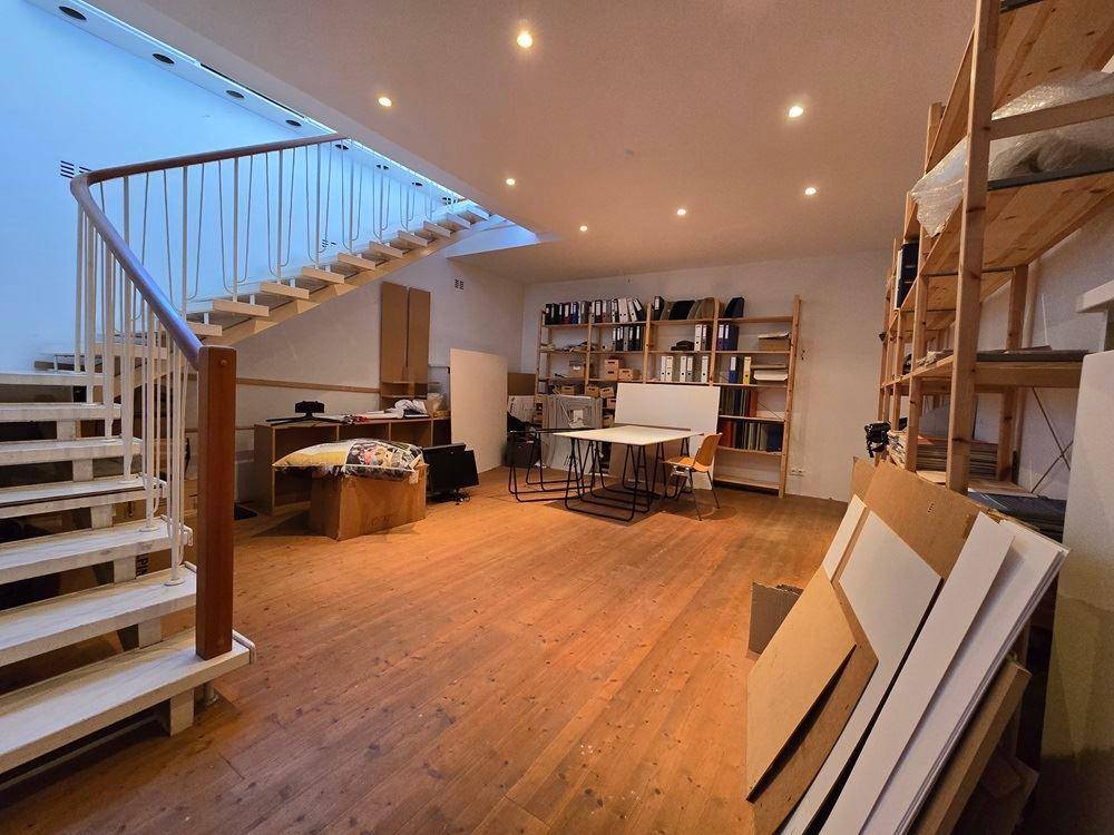 Heller Arbeitsbereich mit einer markanten Holztreppe, Regalen und viel Platz.