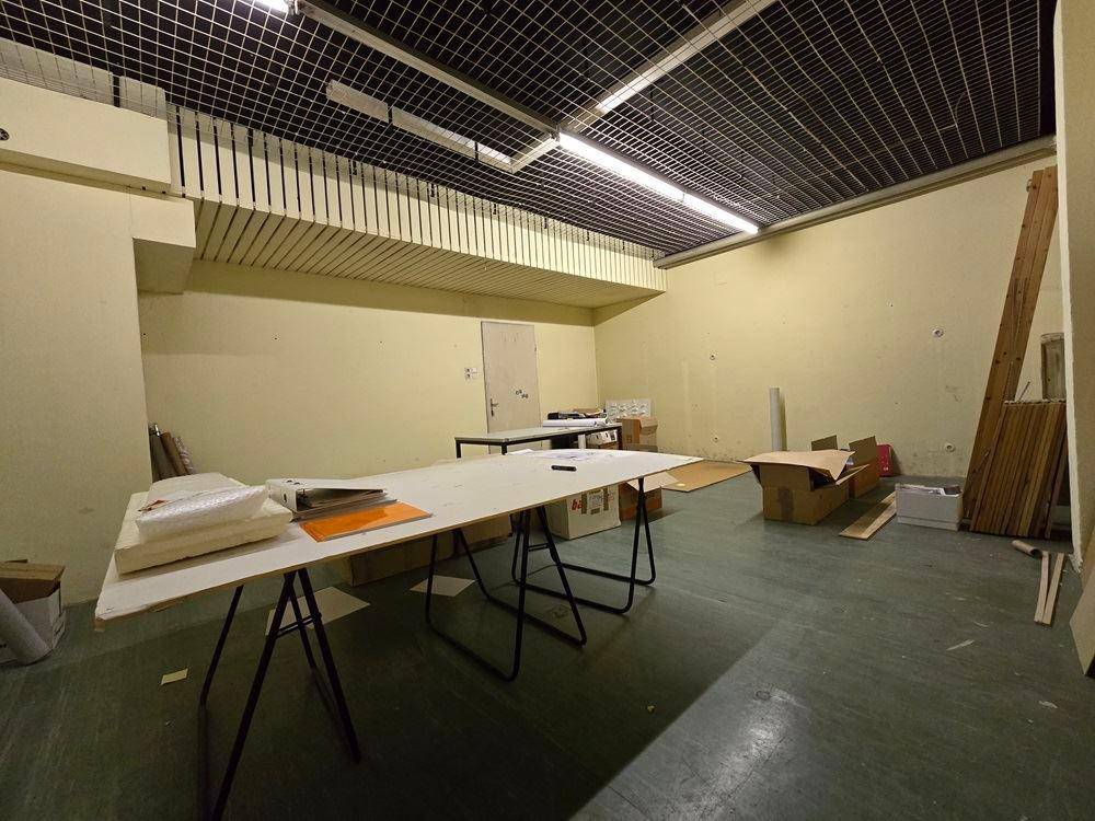 Großer, leerer Raum mit dunklem Boden und Gitterdecke, bereit für verschiedene Nutzungen.
