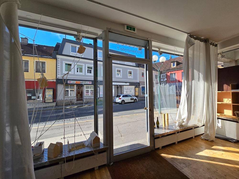 Große Schaufensterfront eines Ladenlokals mit Blick auf die belebte Straße und gegenüberliegende Gebäude.