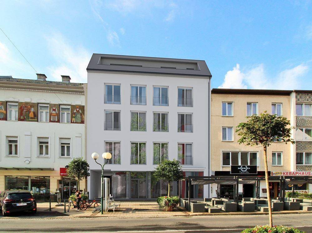 Moderne Gebäudefassade in einer städtischen Umgebung mit großen Fenstern und Geschäften im Erdgeschoss.
