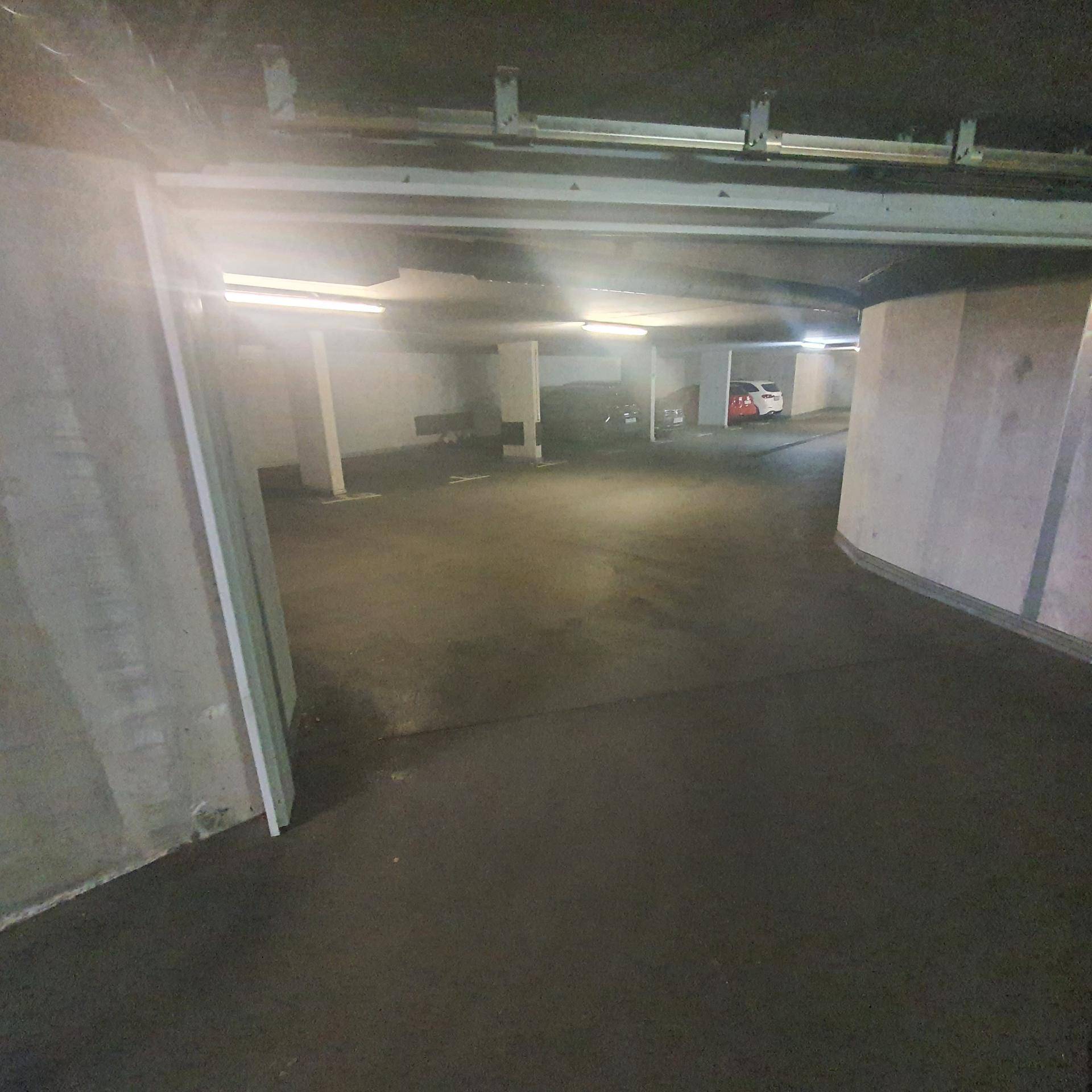 Geräumige Tiefgarage mit vielen Stellplätzen, Betonpfeilern und guter Beleuchtung.