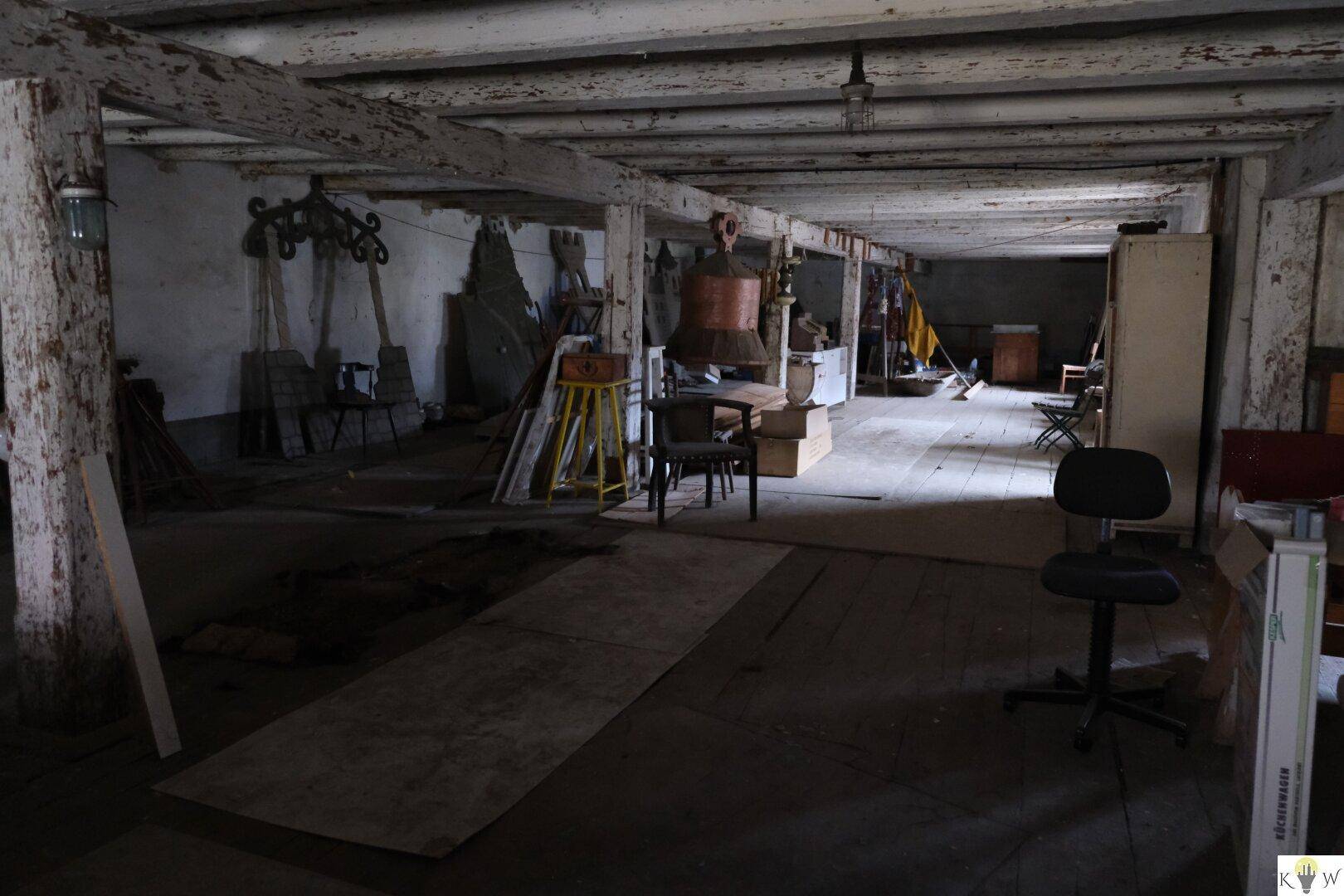 Geräumiger Lagerraum mit Holzbalken, unfertigen Wänden und verschiedenen gelagerten Gegenständen.