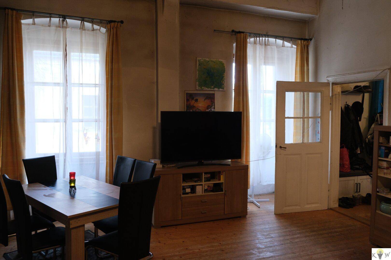 Heller Wohn-Essbereich mit Holzboden, Esstisch und großem Fernseher, ideal für gesellige Abende.