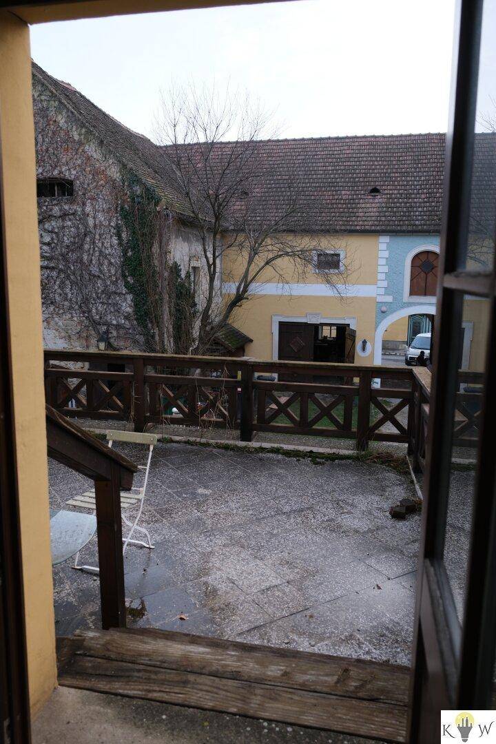 Außenterrasse mit Holzbalkon und Blick auf den historischen Innenhof, ideal zum Entspannen.