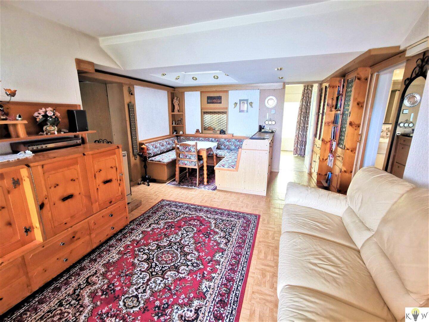 Geräumiger Wohnbereich mit bequemer Couch, Holzeinbauten und traditionellem Teppich.