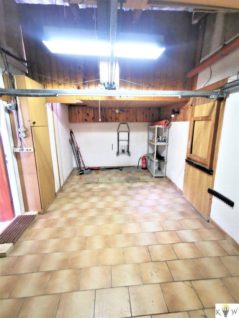 Geräumige Garage mit gefliestem Boden und Stauraum an den Seitenwänden.