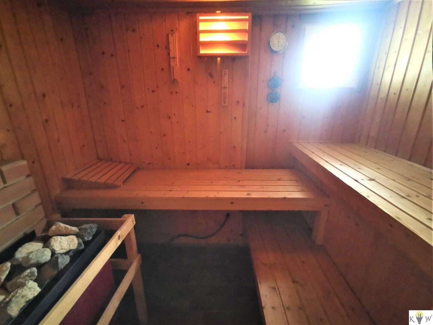 Traditionelle Holzsauna mit Bänken und Heizofen für entspannende Momente.