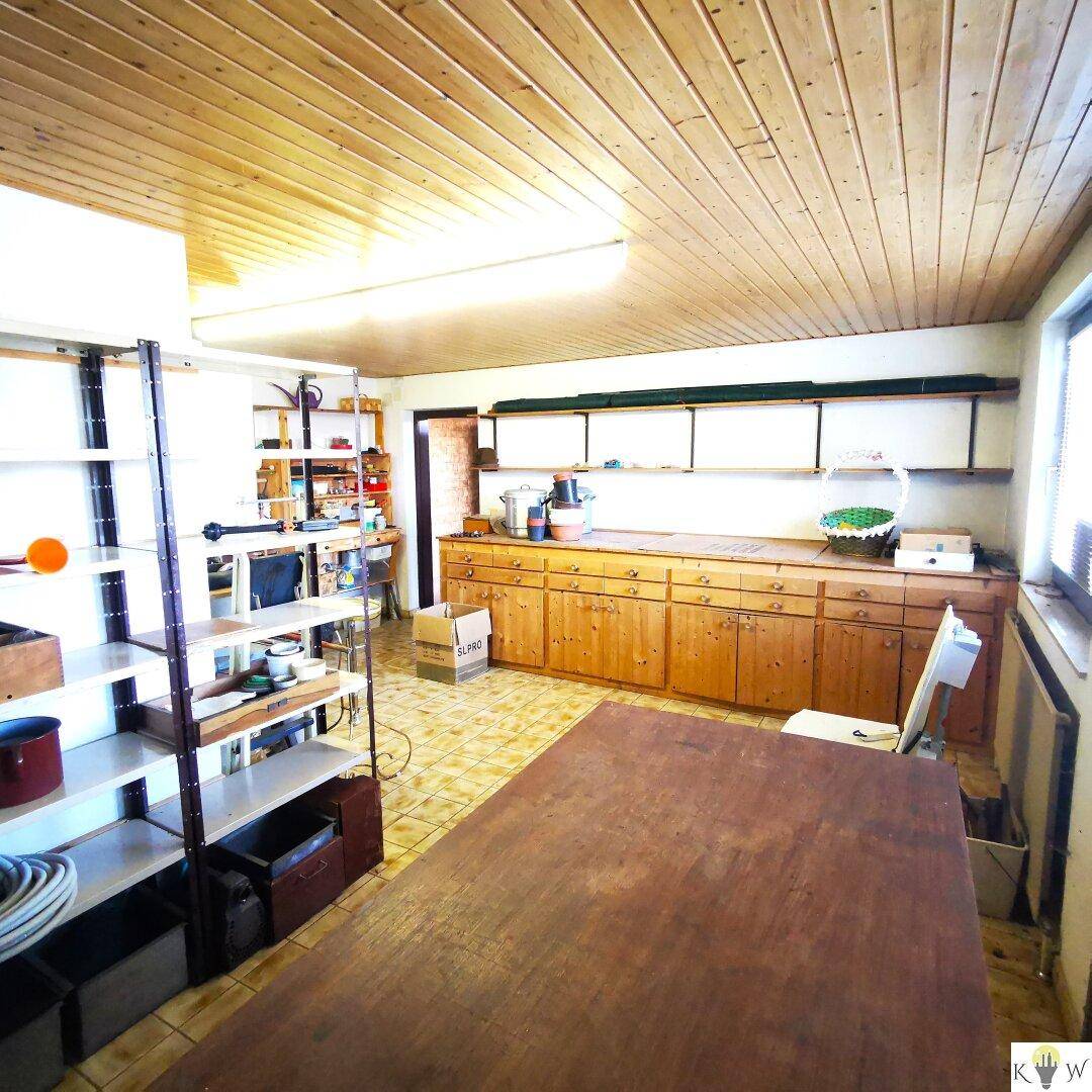 Großer Raum mit Holzschränken, Regalen und Arbeitsfläche, vielseitig nutzbar.