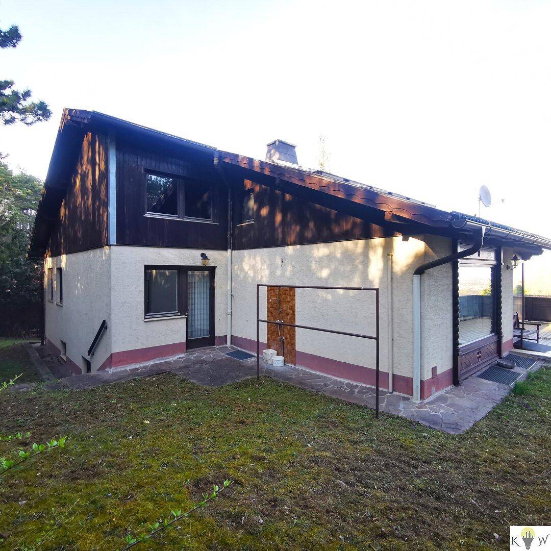 Rückseite des Hauses mit Rasenfläche und Zugang zu einer kleinen Terrasse.