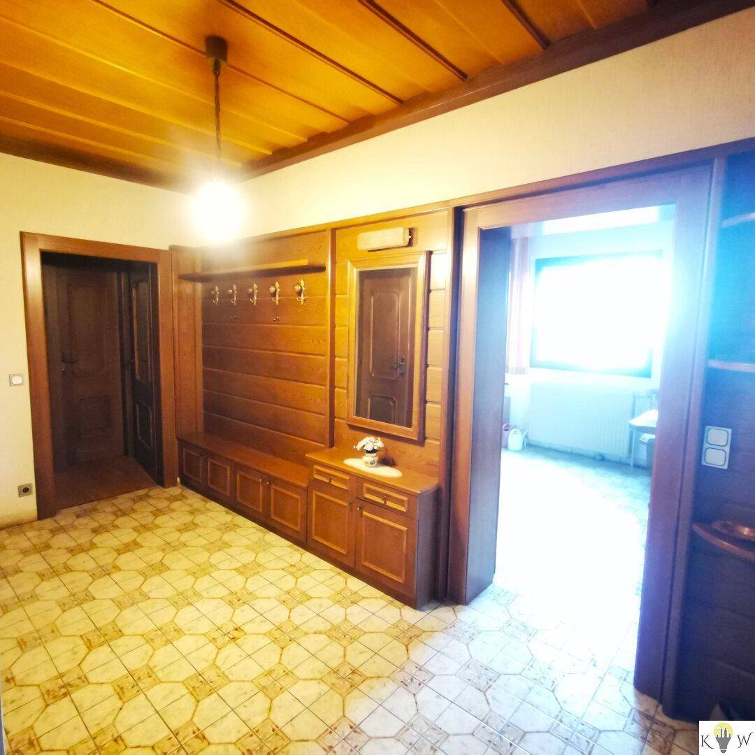 Heller Flur mit Einbaumöbeln aus Holz und Zugang zu weiteren Räumen.