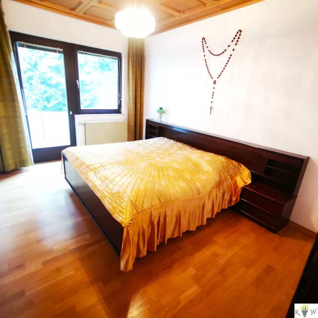 Schlafzimmer mit Holzboden, Doppelbett und großem Fenster mit Blick ins Grüne.