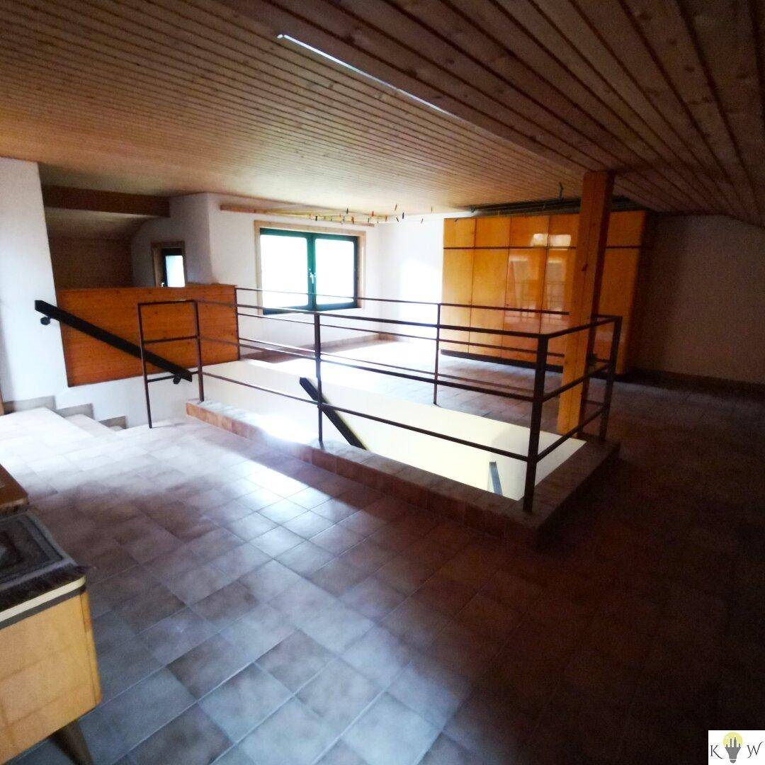 Offener Dachgeschossbereich mit Treppenaufgang und Holzverkleidung.