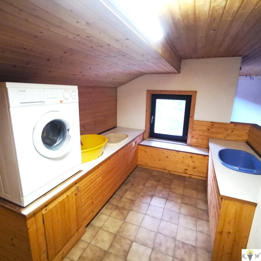 Praktischer Hauswirtschaftsraum im Dachgeschoss mit Waschmaschine und Arbeitsfläche.
