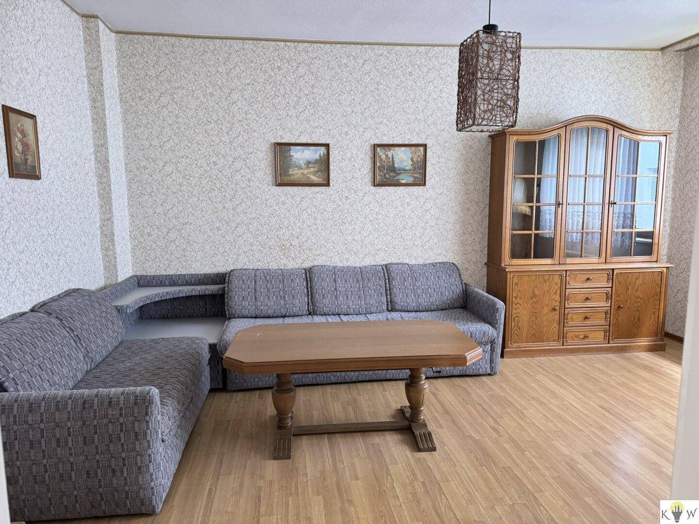 Geräumiges Wohnzimmer mit Ecksofa, Holztisch und Schrank im klassischen Stil.