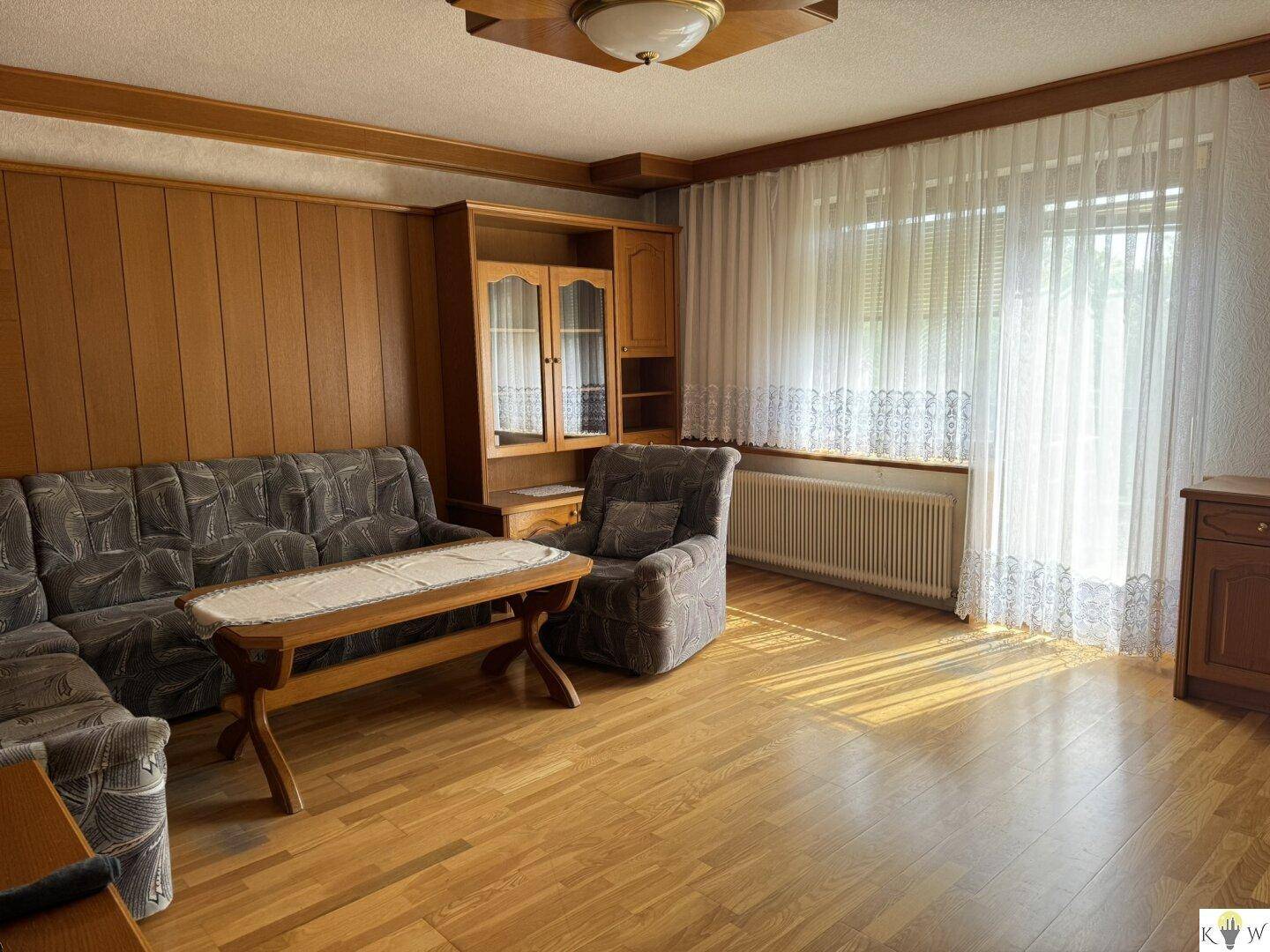 Helles Wohnzimmer mit Holzvertäfelung, Sofa und großem Fenster.