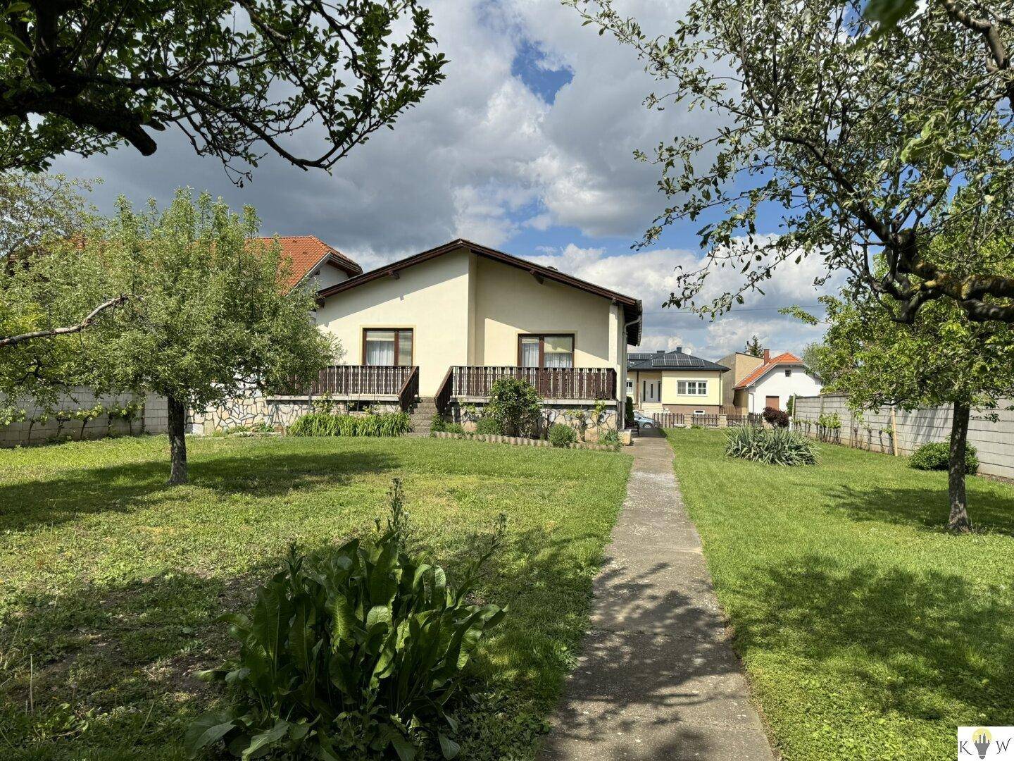 Freistehendes Haus mit großem Garten und Obstbäumen unter bewölktem Himmel.