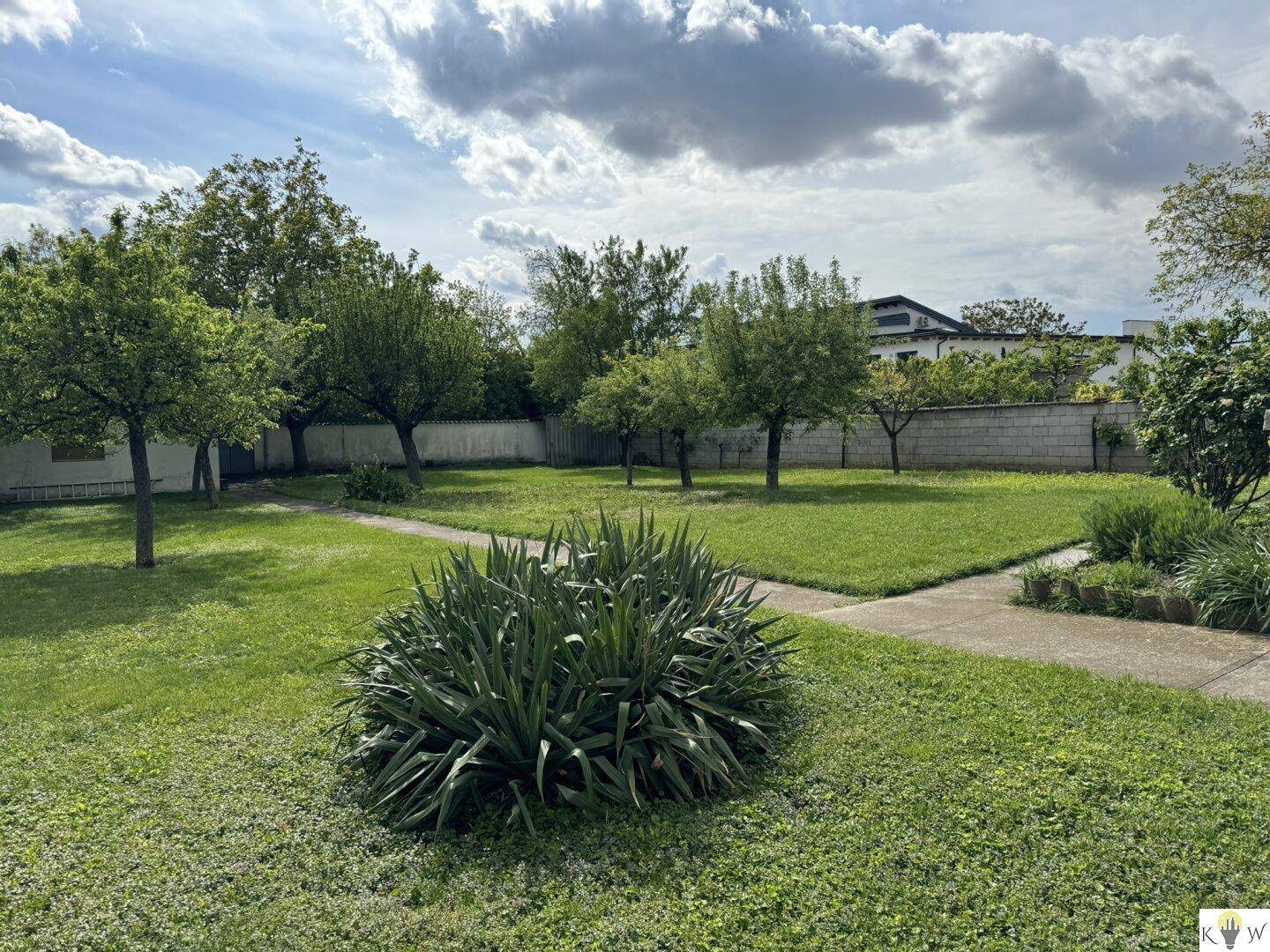 Großer, gepflegter Garten mit Rasenflächen, Sträuchern und Bäumen.