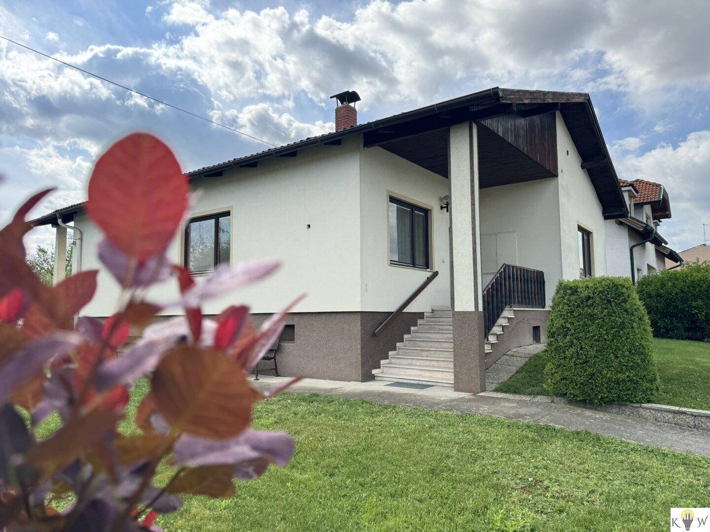 Seitenansicht des Hauses mit Eingangsbereich und gepflegter Grünfläche.