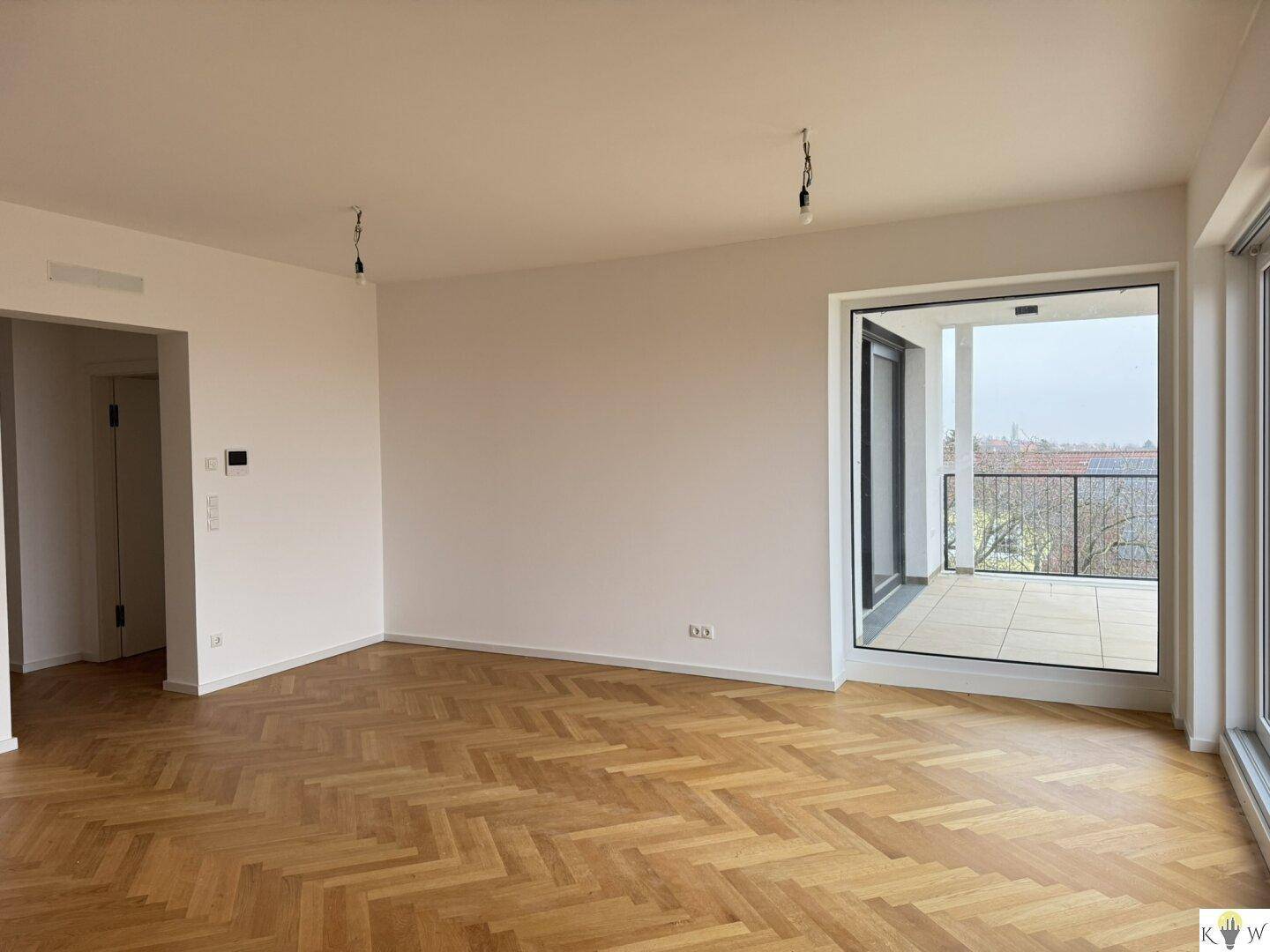 Heller Wohnbereich mit Parkettboden und großem Fenster mit Zugang zur Terrasse und Weitblick.