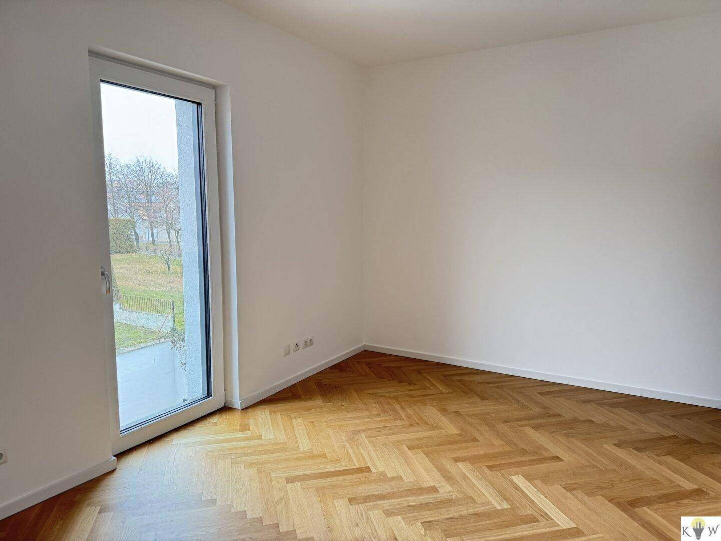Ruhiges Zimmer mit Parkettboden und Fenster mit Blick auf die grüne Umgebung.