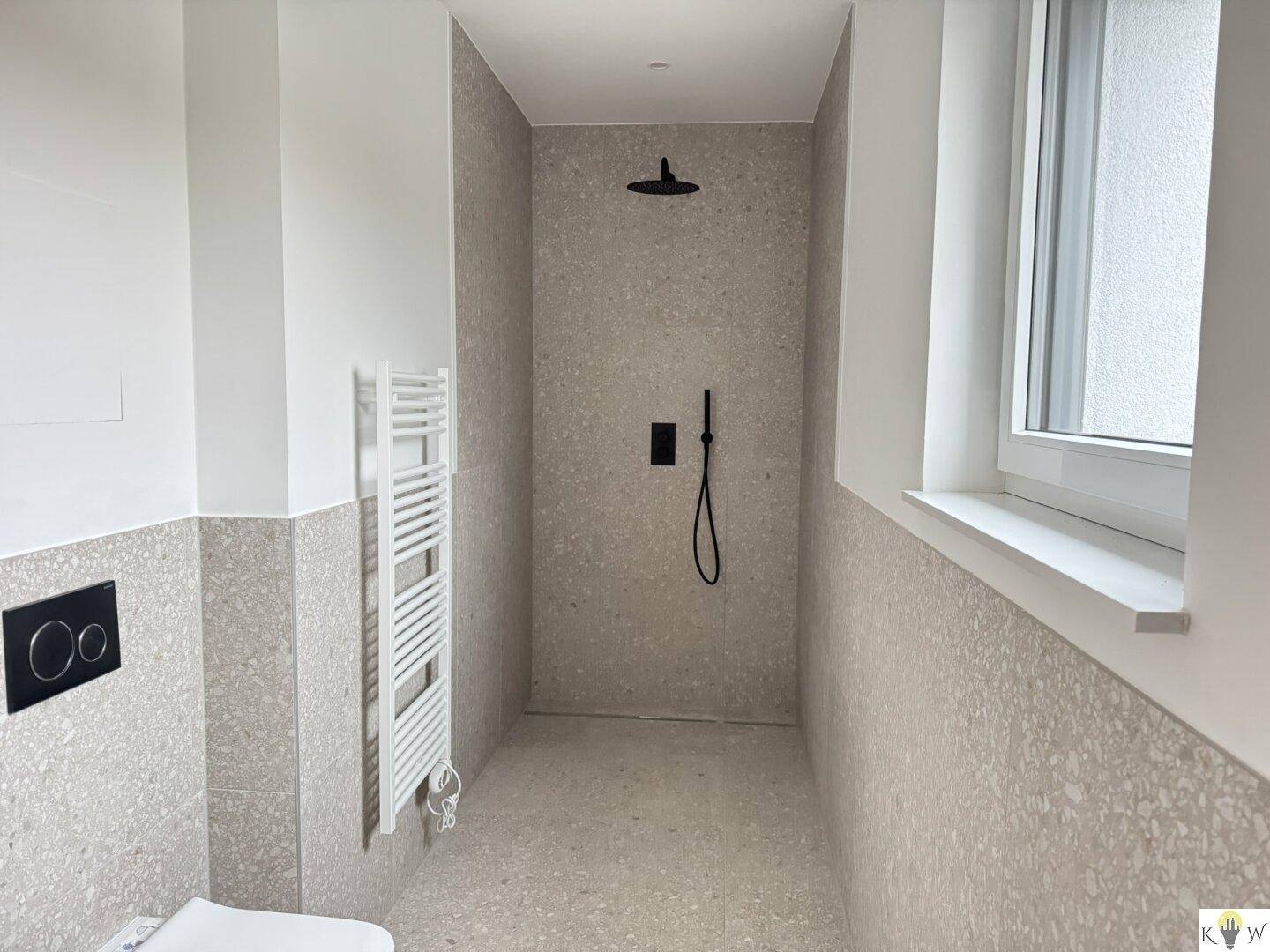 Geräumige, moderne Dusche mit Regenduschkopf und beheiztem Handtuchhalter im Badezimmer.