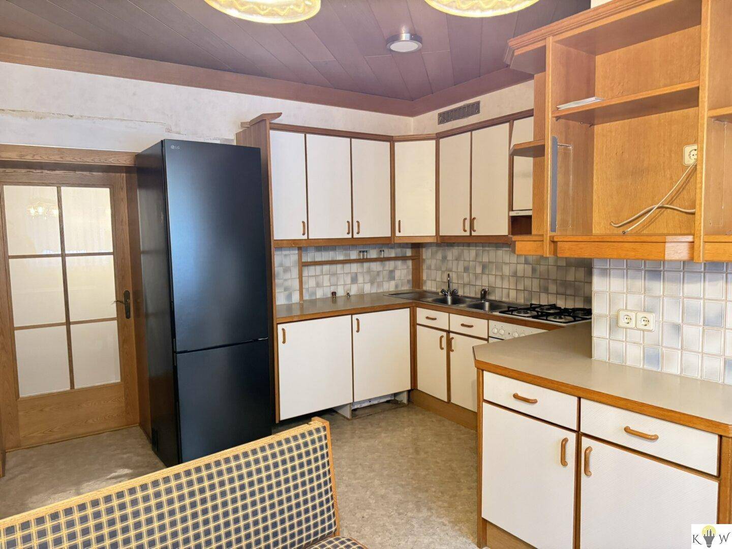 Traditionelle Küche mit Holzdecke, weißen Schränken und einem großen Kühlschrank.