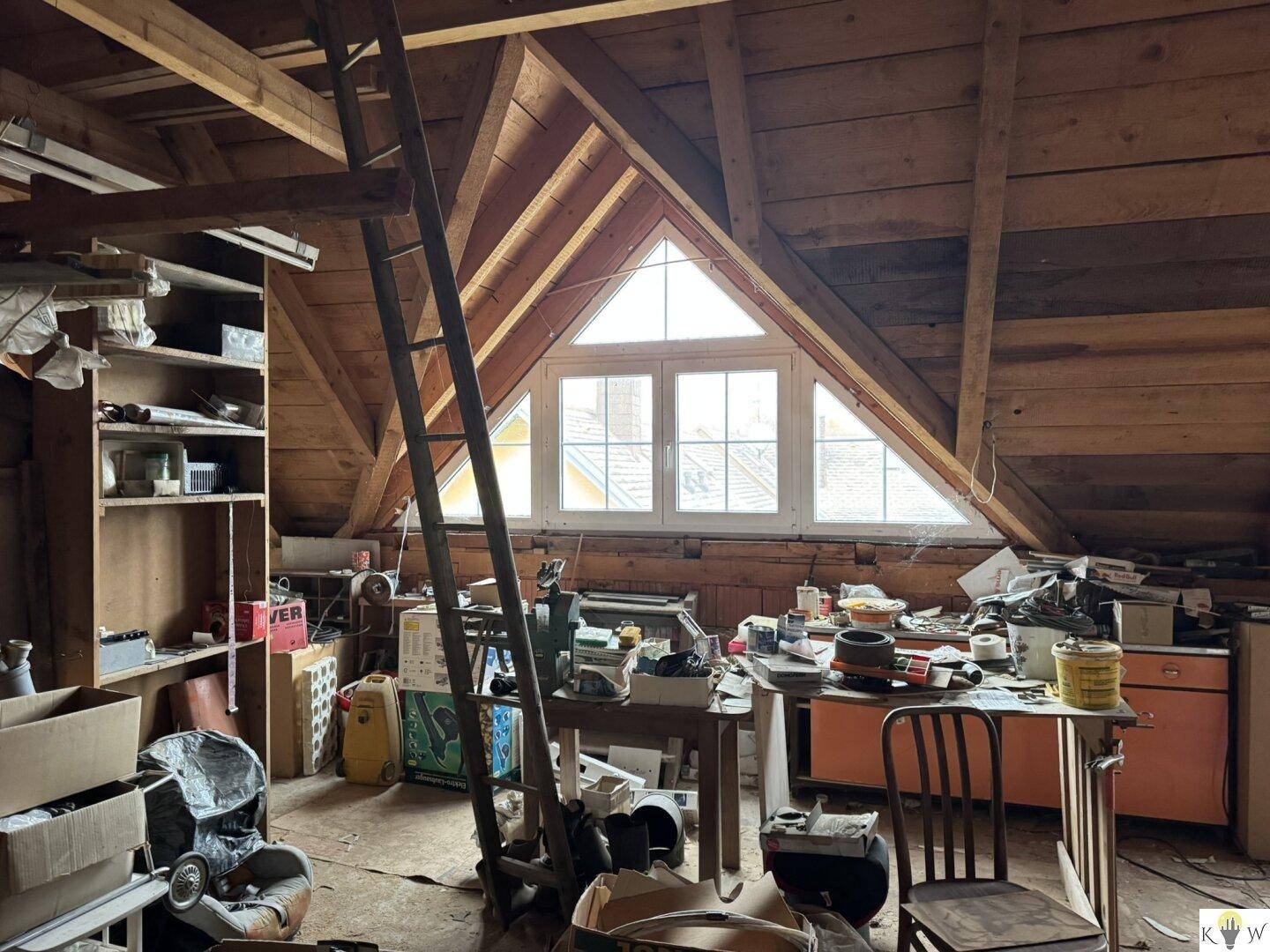 Ausgebauter Dachboden mit Holzkonstruktion, großem Fenster und Stauraum.
