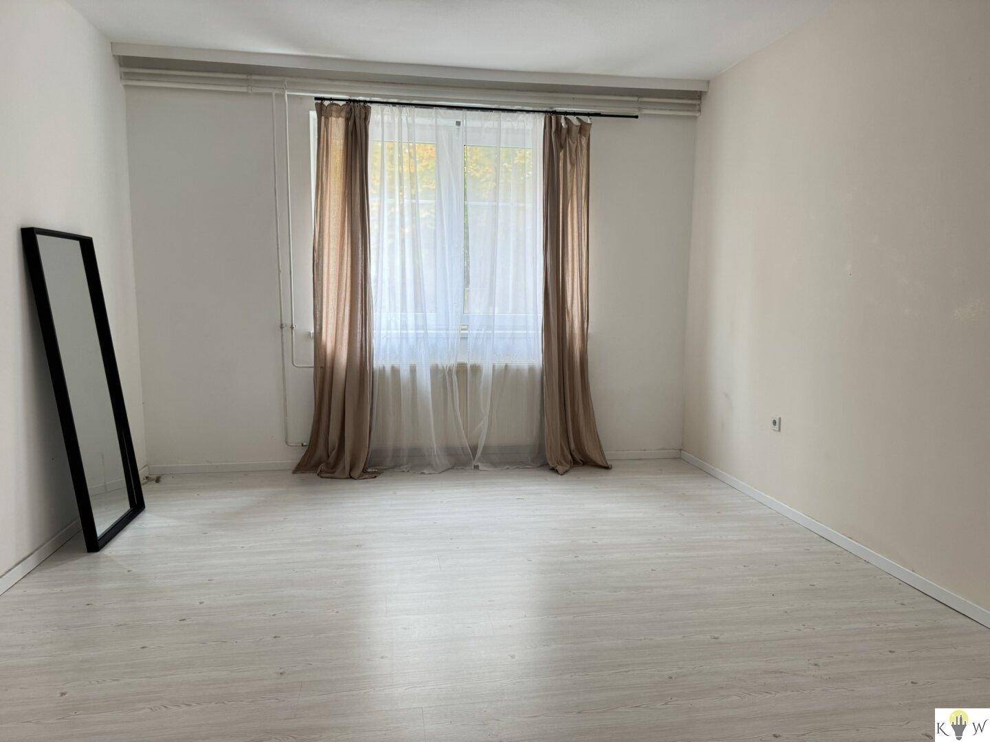 Helles, leeres Zimmer mit neuem Laminatboden und großen Fenstern.
