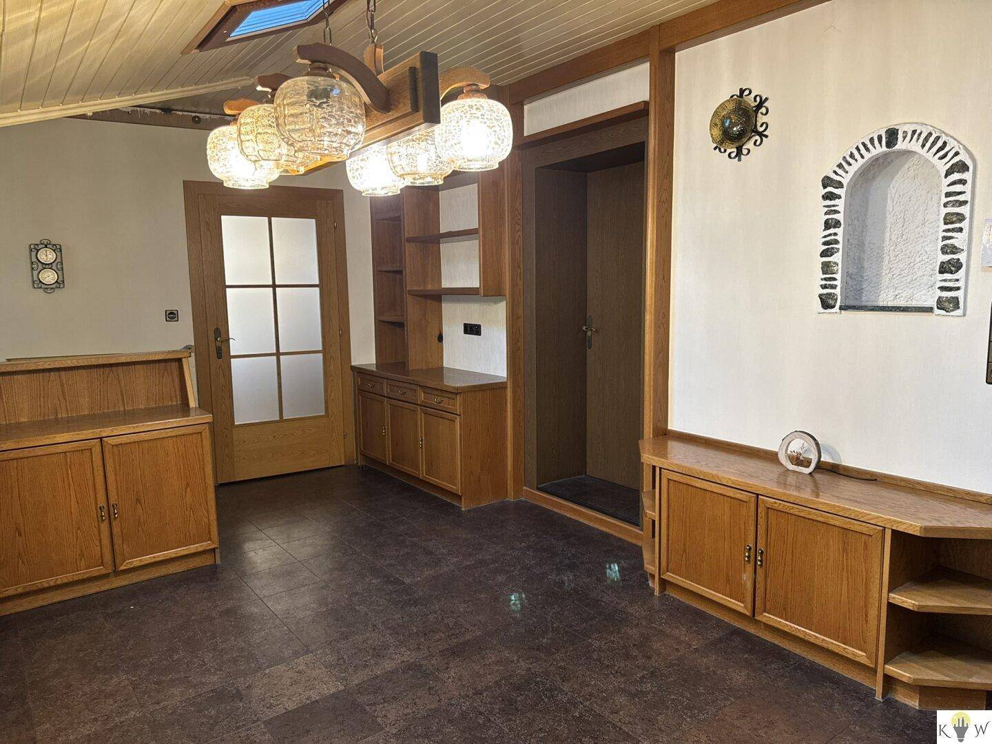 Wohnbereich mit Holzvertäfelung, dunklem Boden und dekorativer Nische in der Wand.