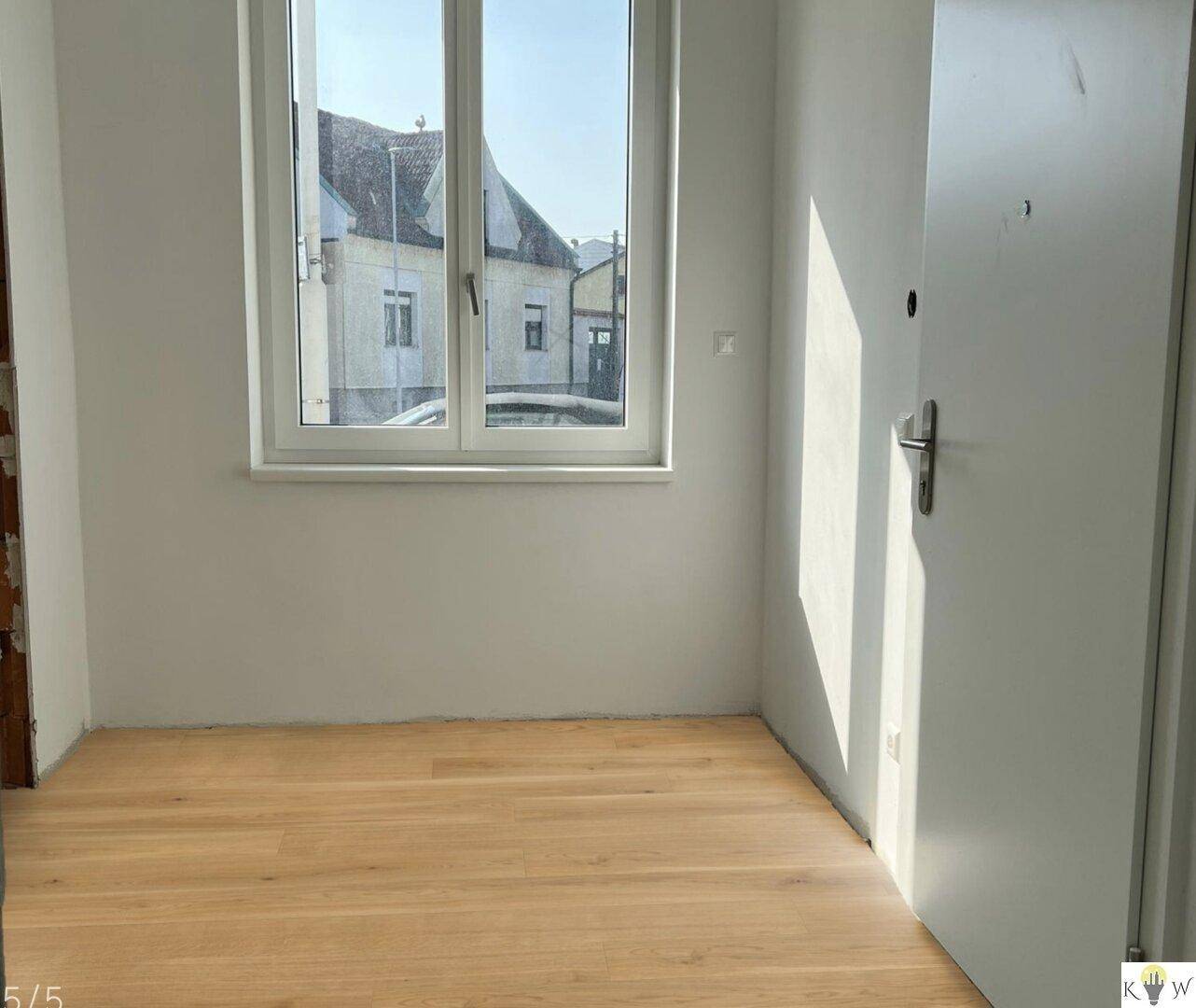Sonniger Raum mit Holzboden und Blick auf die Nachbarschaft, ideal für ein Schlafzimmer.