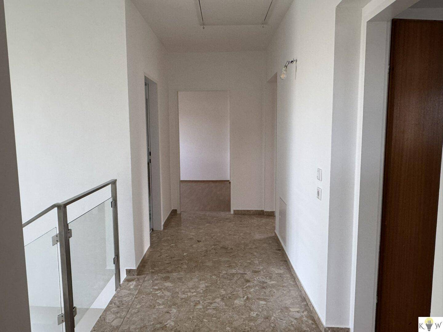Heller Flur im Obergeschoss mit Fliesenboden und Blick in weitere Räume.