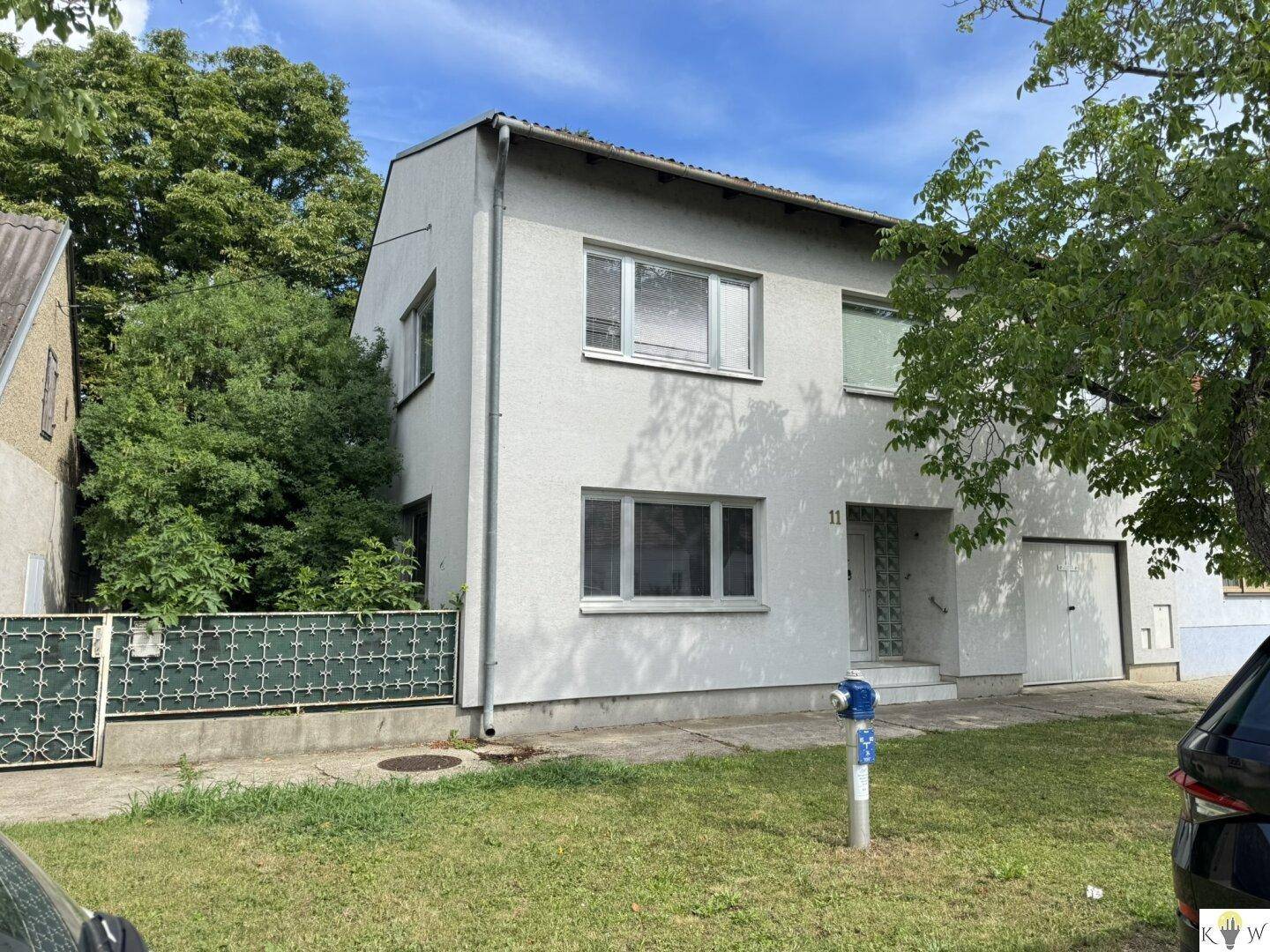 Einfamilienhaus mit weißer Fassade, mehreren Fenstern und integrierter Garage.
