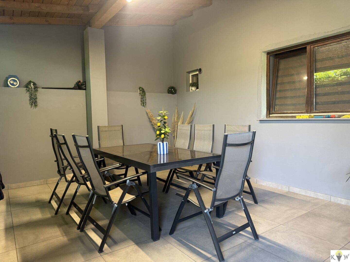 Überdachter Außenbereich mit Esstisch und Stühlen, ideal für Mahlzeiten im Freien.