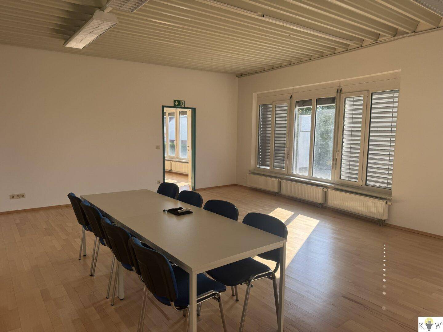 Geräumiger Konferenzraum mit Holzboden und einem großen Tisch für Besprechungen.