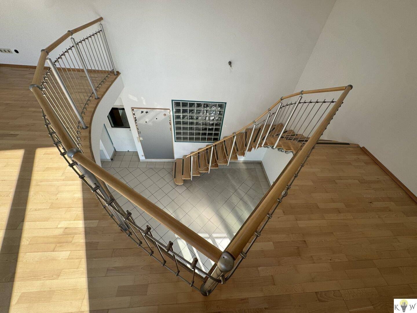Elegante Wendeltreppe mit Holzstufen und Metallgeländer, die die Etagen verbindet.