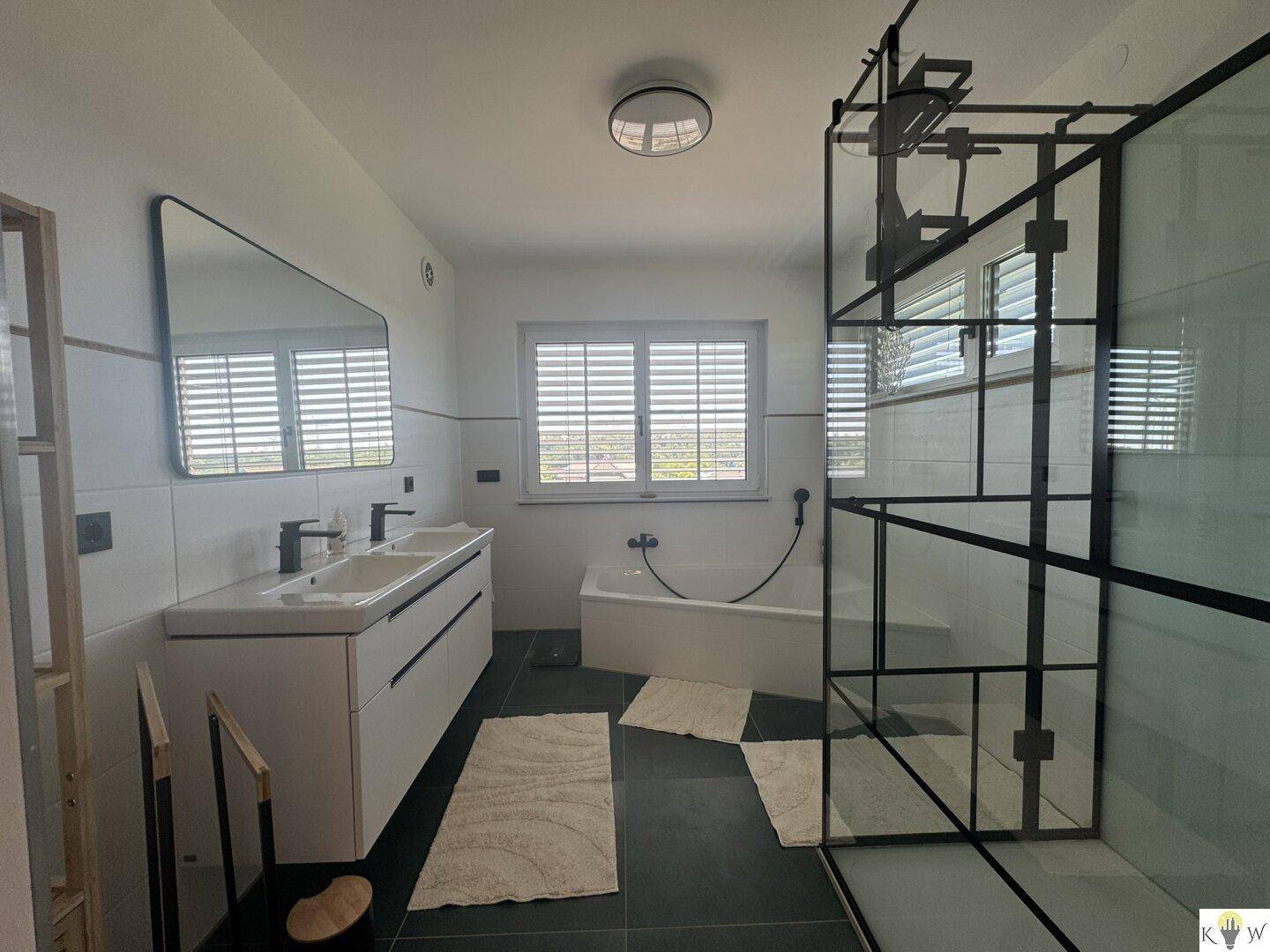 Modernes Badezimmer mit Doppelwaschbecken, Badewanne und großer Duschkabine.