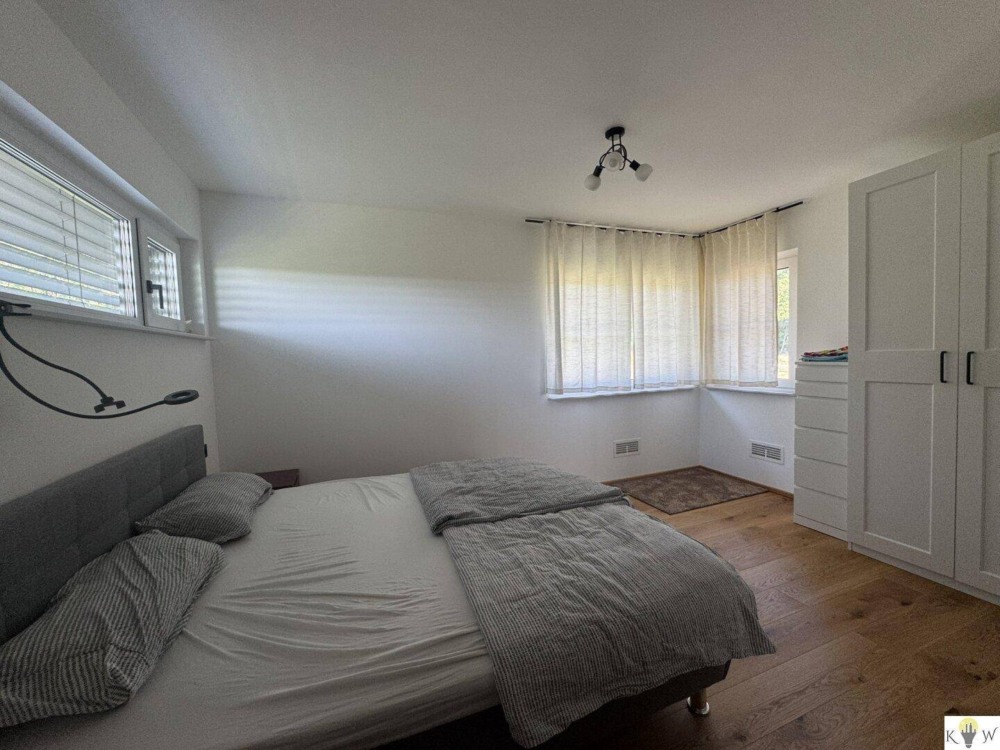 Helles Schlafzimmer mit Doppelbett, Einbauschränken und Holzboden.