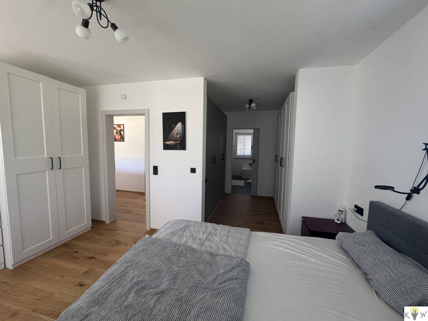 Schlafzimmer mit Doppelbett, Zugang zum Ankleidezimmer und Holzboden.