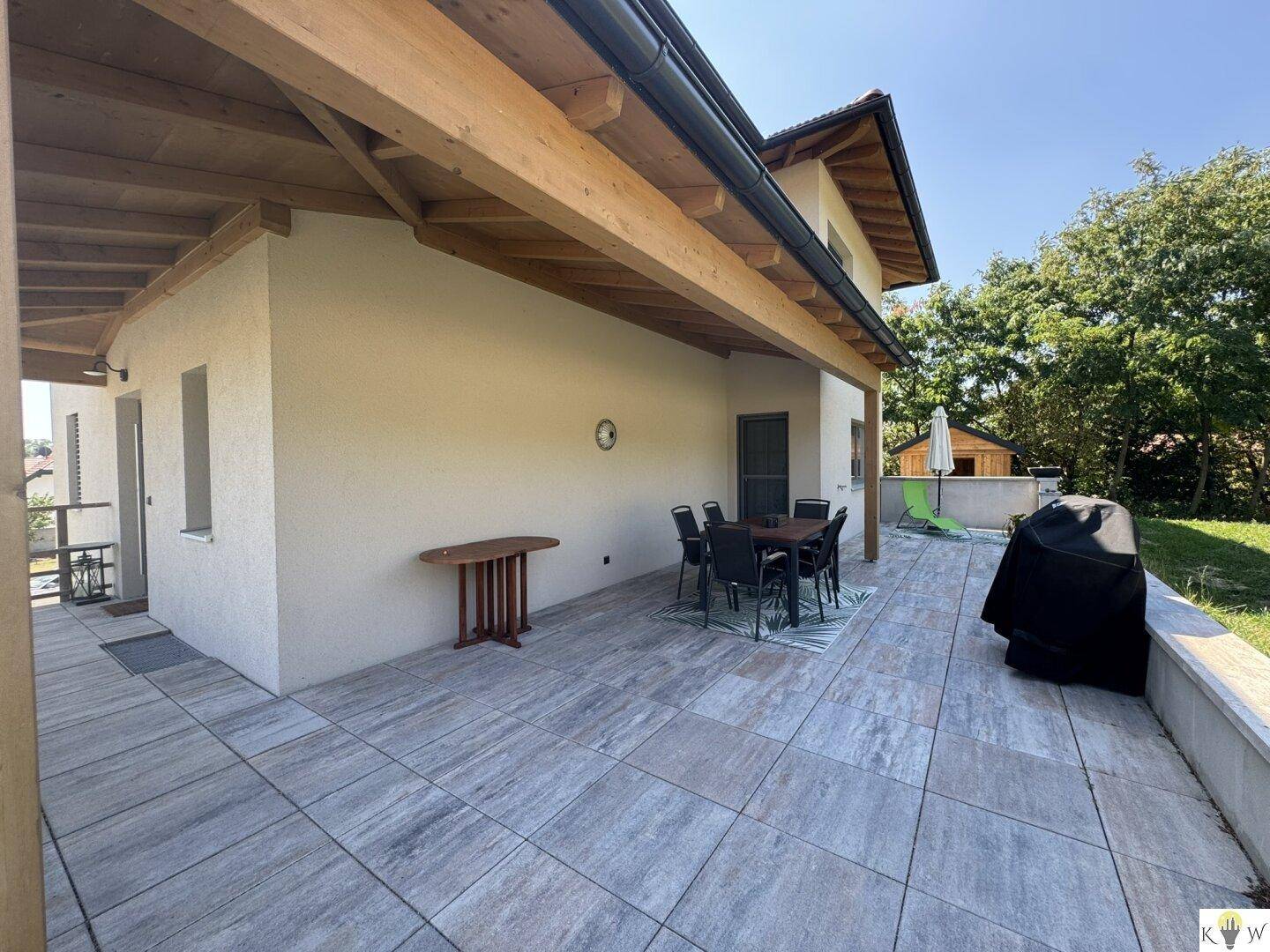 Große, geflieste Terrasse am Haus mit Holzbalken und Essbereich im Freien.
