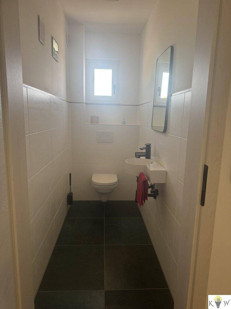 Kleines Gäste-WC mit Fenster, Wand-WC und modernem Waschbecken.