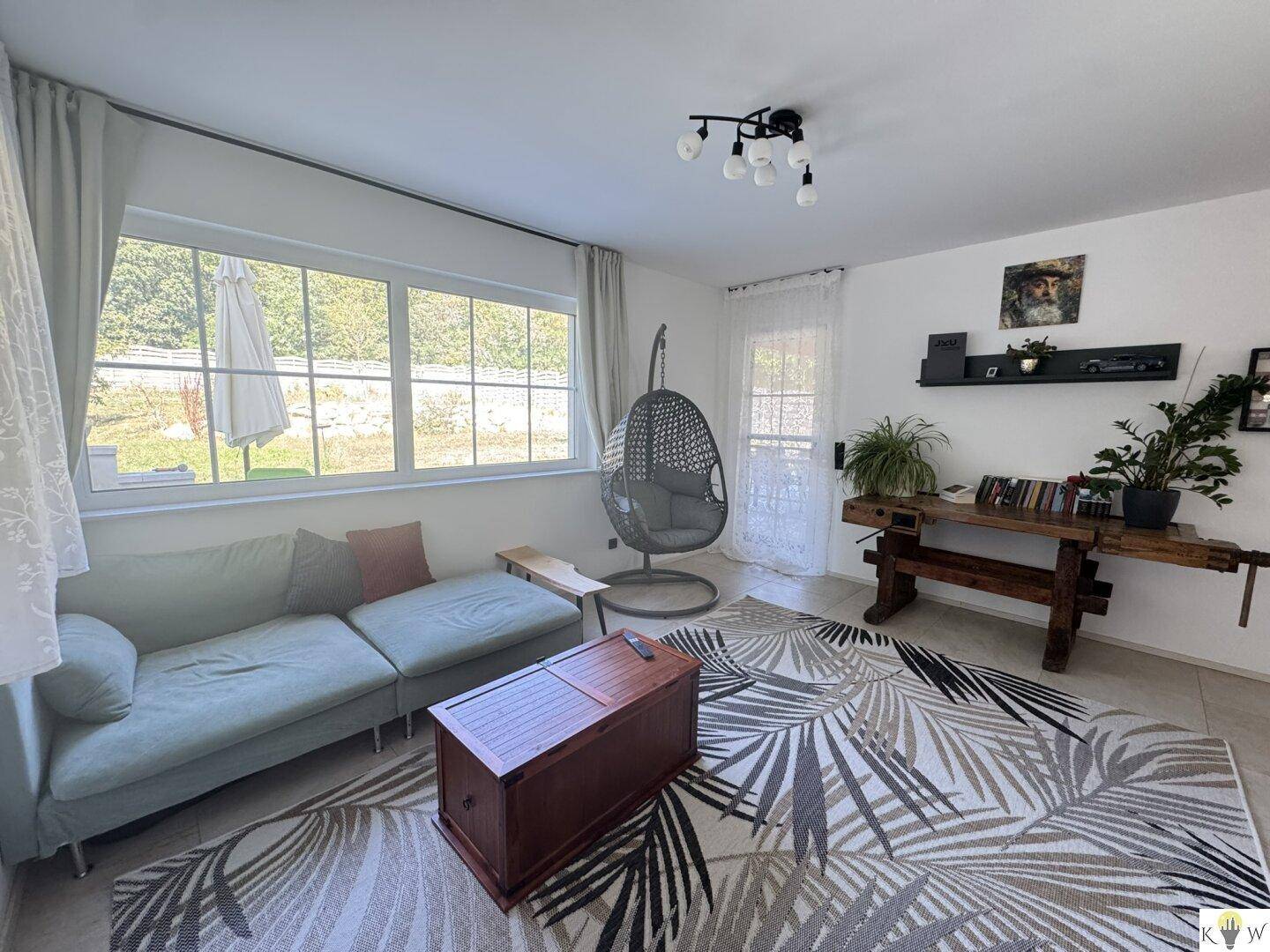 Helles Wohnzimmer mit bequemer Couch, dekorativem Teppich und viel Tageslicht.
