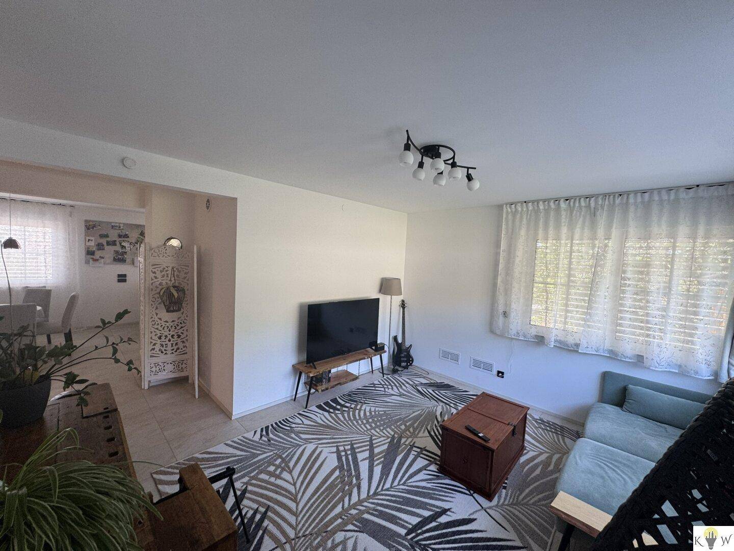 Geräumiges Wohnzimmer mit Fernseher, Sofa und Blick auf den Essbereich.