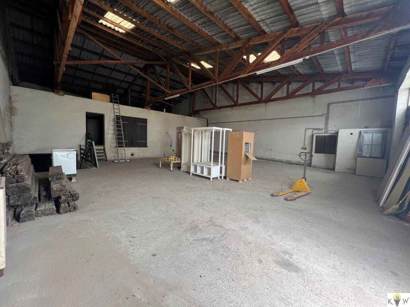 Große, leere Lagerhalle mit sichtbarer Holzkonstruktion des Daches und Betonboden.