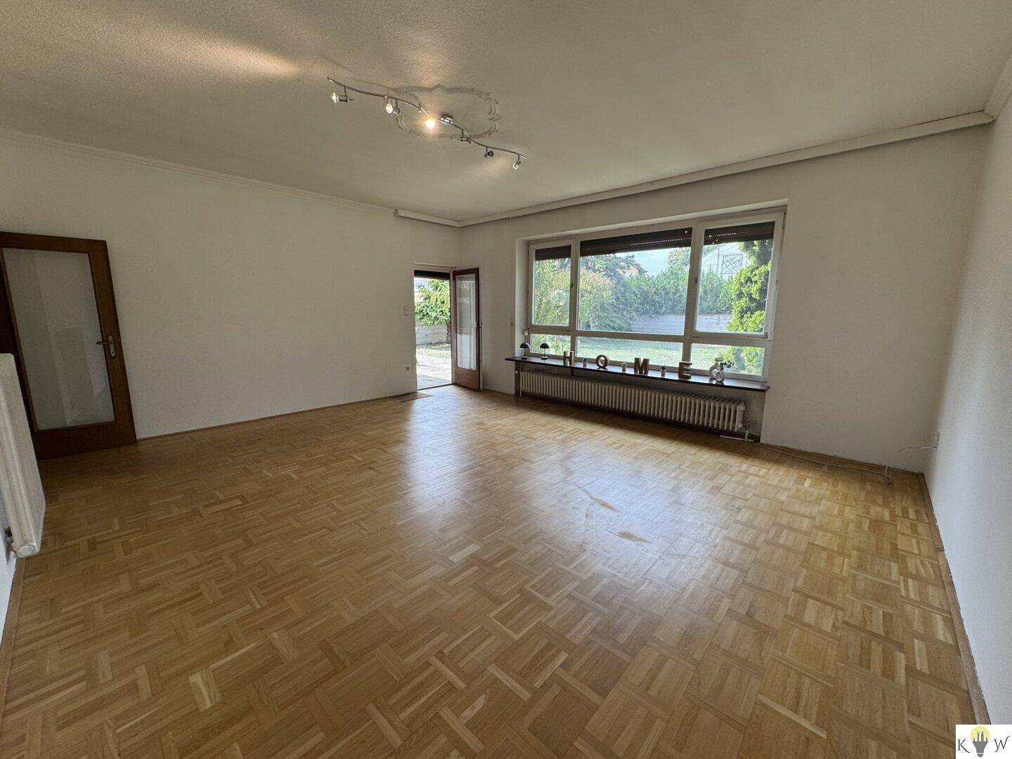 Helles Wohnzimmer mit Parkettboden und direktem Zugang zur Terrasse und zum Garten.