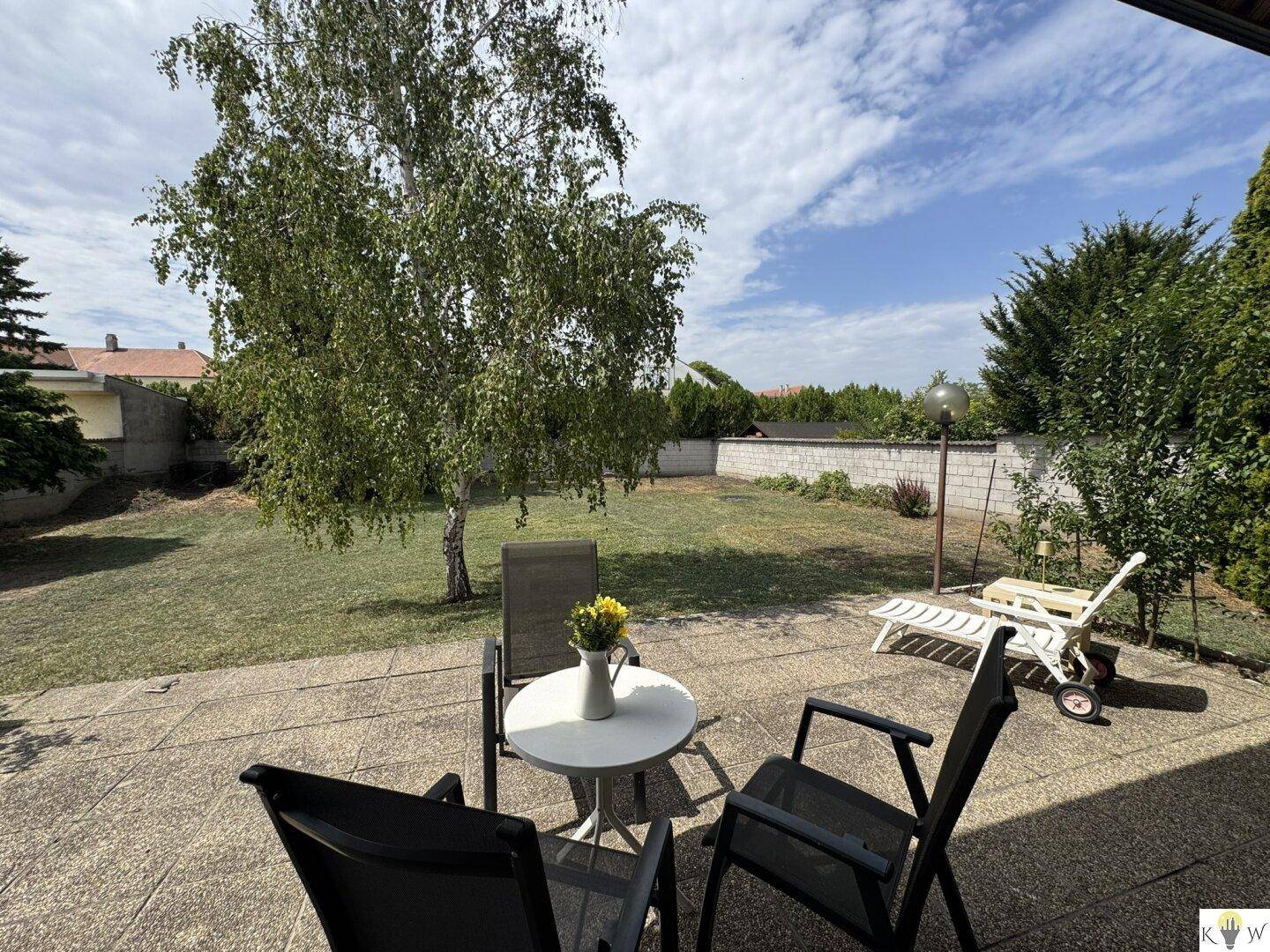 Großer Garten mit Rasenfläche und Sitzgelegenheiten unter einem Baum, ideal zum Entspannen.