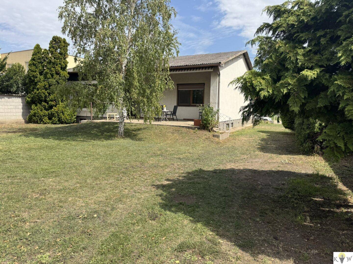 Seitenansicht des Hauses mit Garten und Zugang zur Terrasse, umgeben von viel Grün.