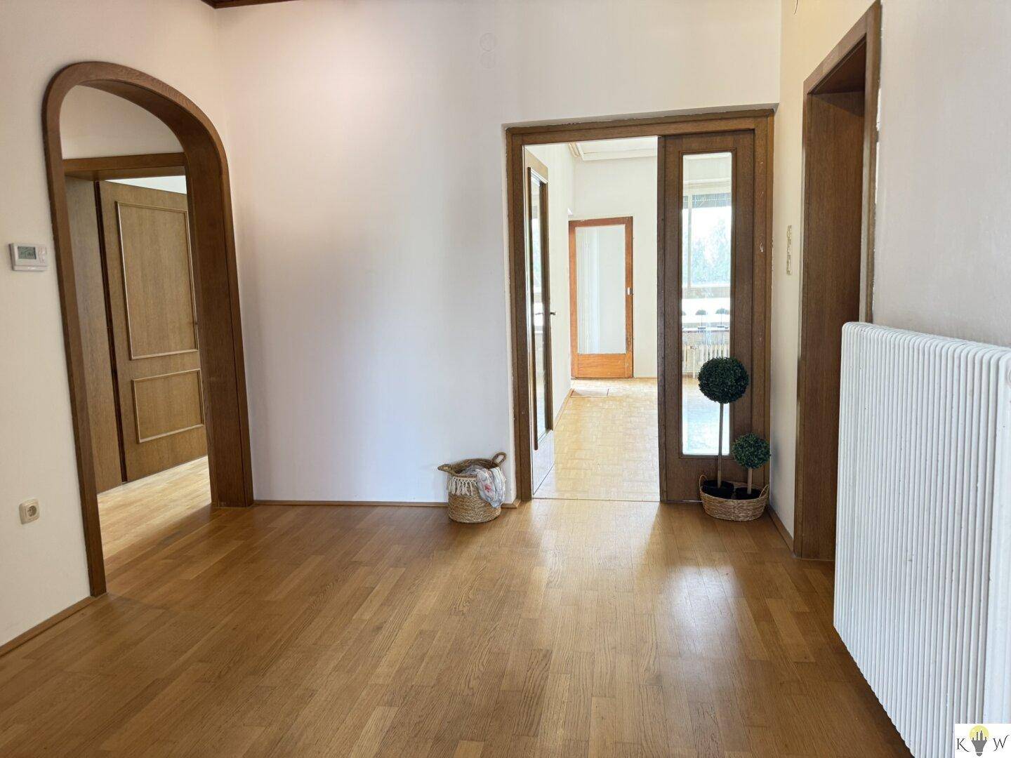 Heller Flur mit Holzboden und Durchgängen zu verschiedenen Zimmern, bietet eine offene Atmosphäre.