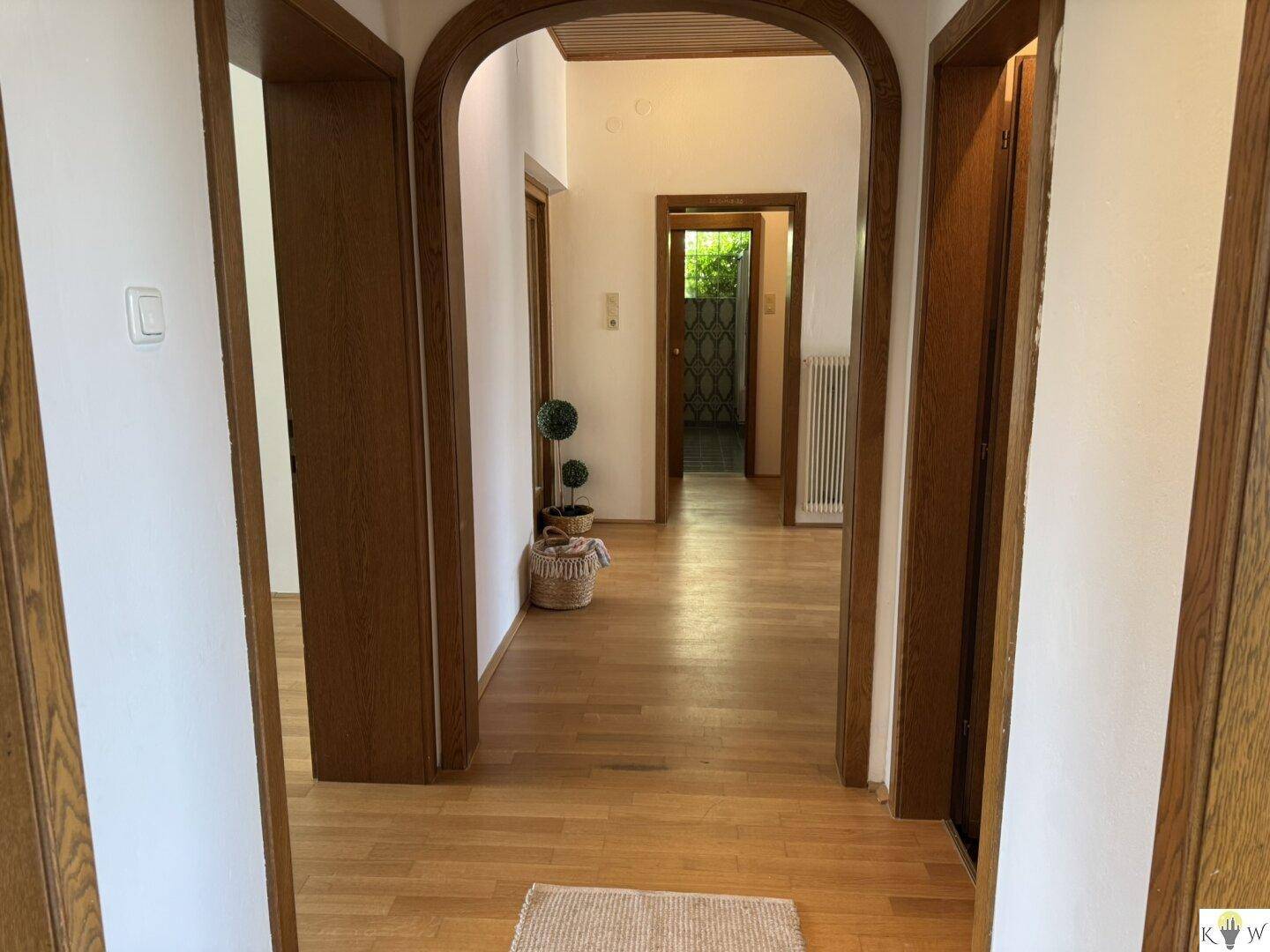 Langer Flur mit Holzboden und Holztüren, der verschiedene Bereiche des Hauses verbindet.
